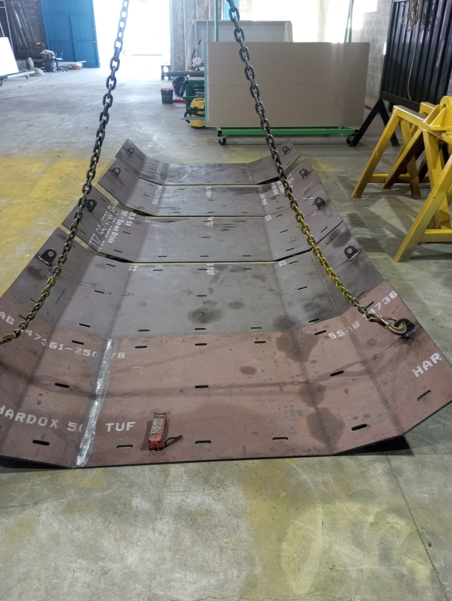 Plancha de Hardox 500 TUF con tres pliegues longitudinales, colgando del puente grúa, recién salida de la prensa
